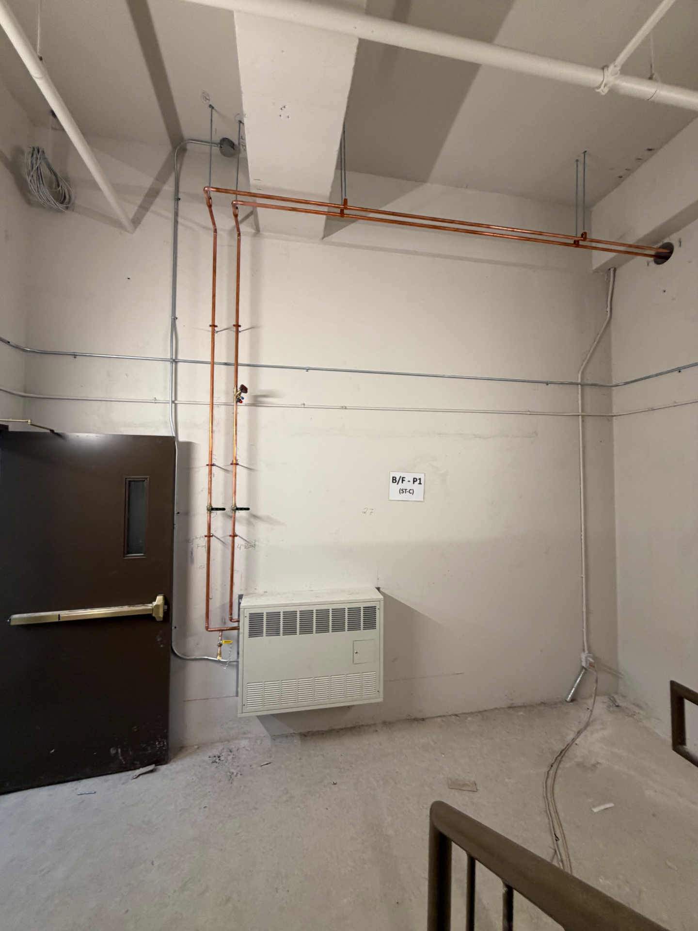 New copper plumbing run along the wall and ceiling of a utility room