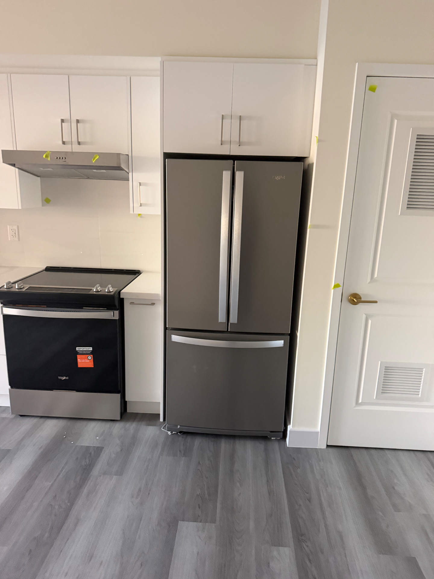 Close view of a newly installed stove, refrigerator and trim in a renovated kitchen